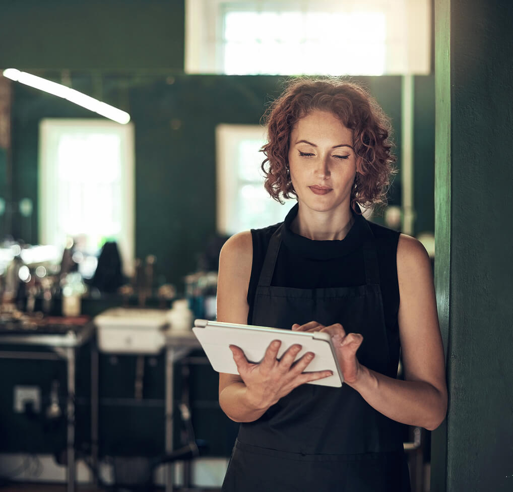A hand holding a smartphone displaying an app in a blurred grocery store aisle with bright overhead lighting.